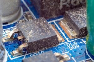 Bližnji pregled umazanega elektronskega čipa na plošči tiskanega vezja pred ultrazvočnim čiščenjem.